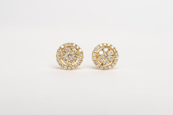 Timeless and modern, you will fall in love with these stunners. A beautiful round brilliant diamond in the center with smaller diamonds set in a halo. They are perfect for any ear.  18kt yellow gold Total diameter of the earring 5.6mm 3mm x 2 diamond center stone Center stone set with four claws Total dia