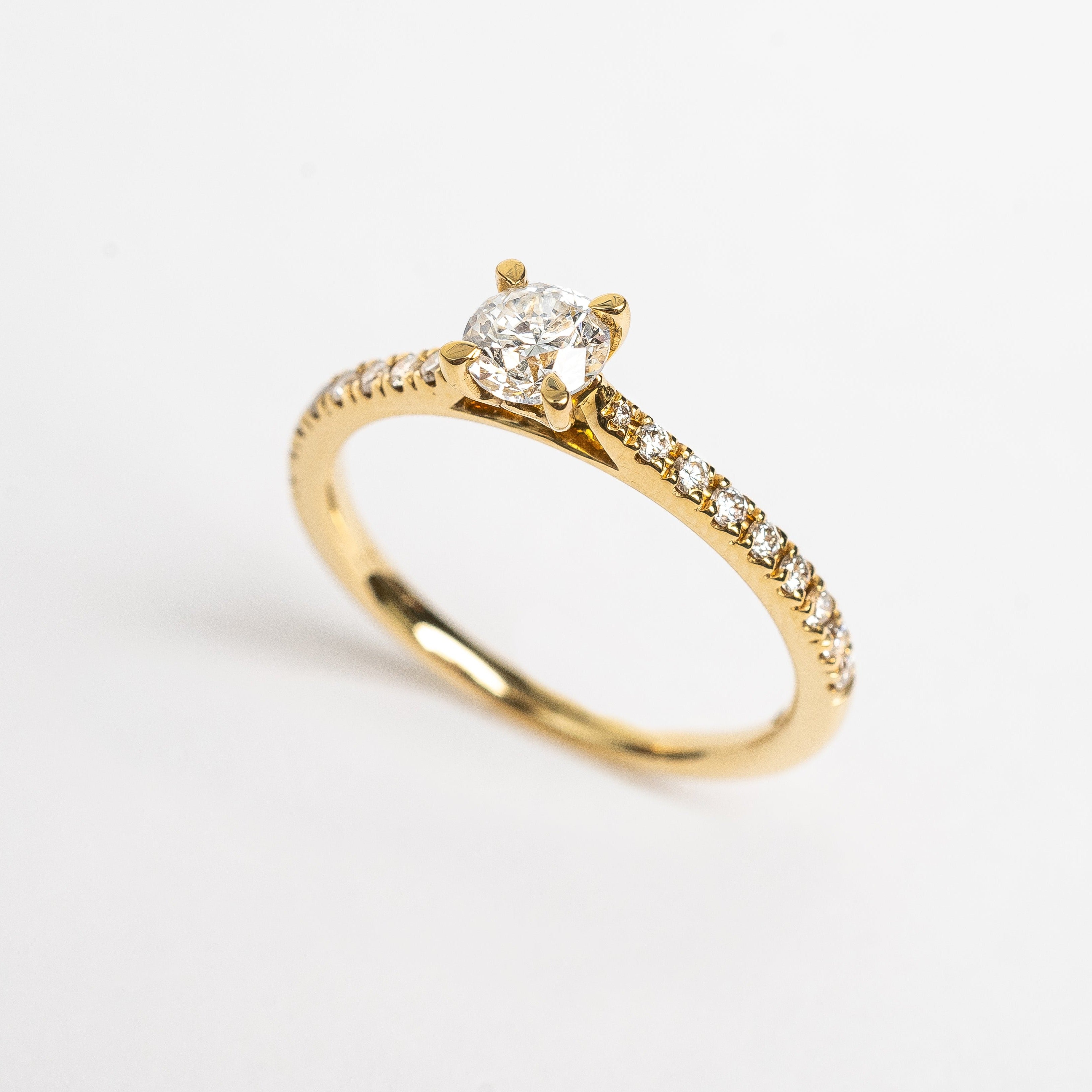 This yellow gold diamond ring is set with diamonds over half the band. This ring is a classic and precious design. We also have this ring available without the diamonds on the band if you are look for something even more timeless.  18kt yellow gold. Perfect engagement ring.