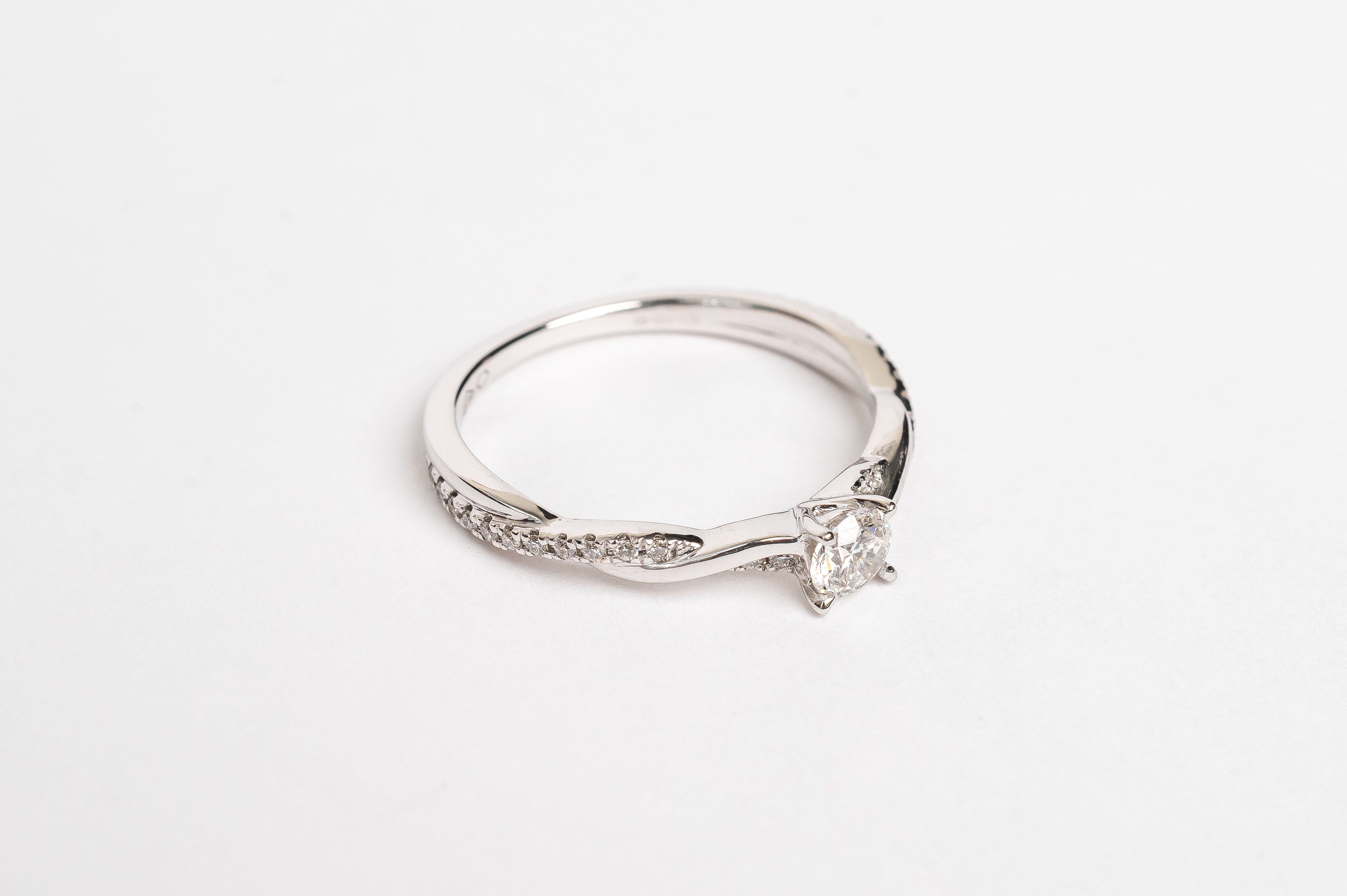 This white gold braided diamond ring is made out of two bands crossing over and over to make a braided twisty design. The crossing band is set with diamonds for a playful result. The beautiful center diamond gives your ring a nice look. 