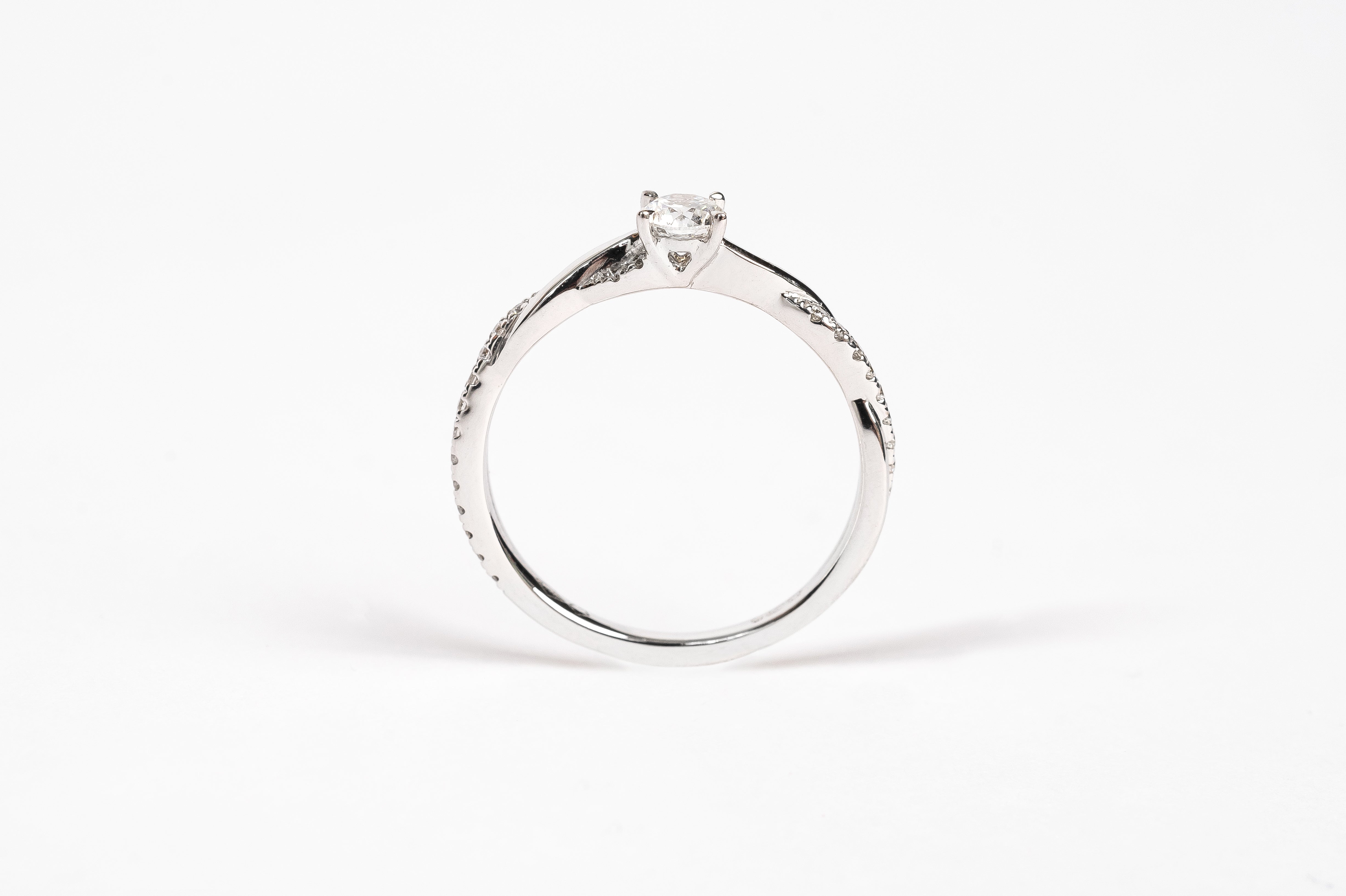 This white gold braided diamond ring is made out of two bands crossing over and over to make a braided twisty design. The crossing band is set with diamonds for a playful result. The beautiful center diamond gives your ring a nice look. 