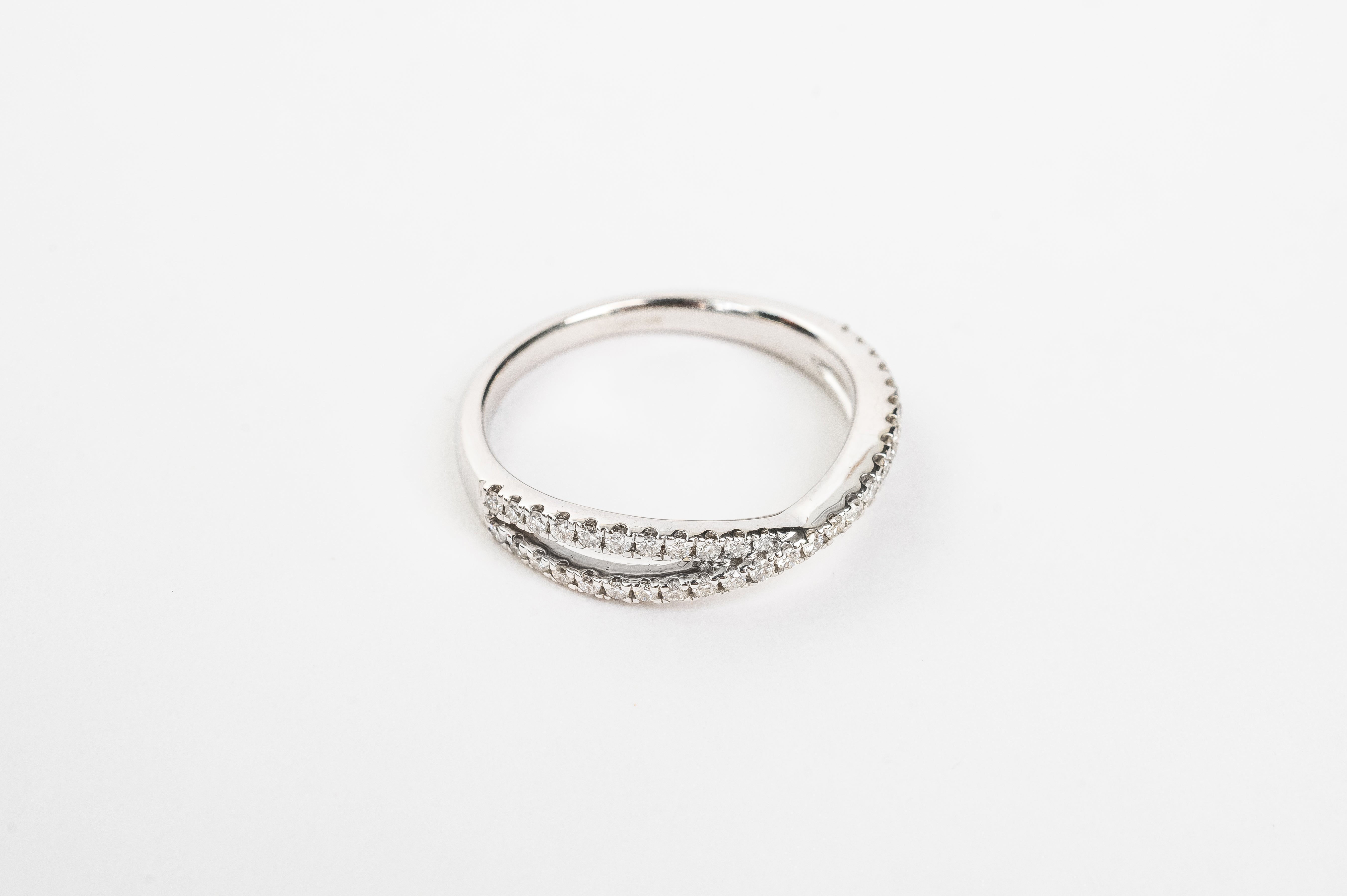 This cross over ring is made out of one band splitting into two diamond set bands and crossing in the middle. It is stunning! This ring can be worn alone or stacked together with others. What's your style?   18kt white gold