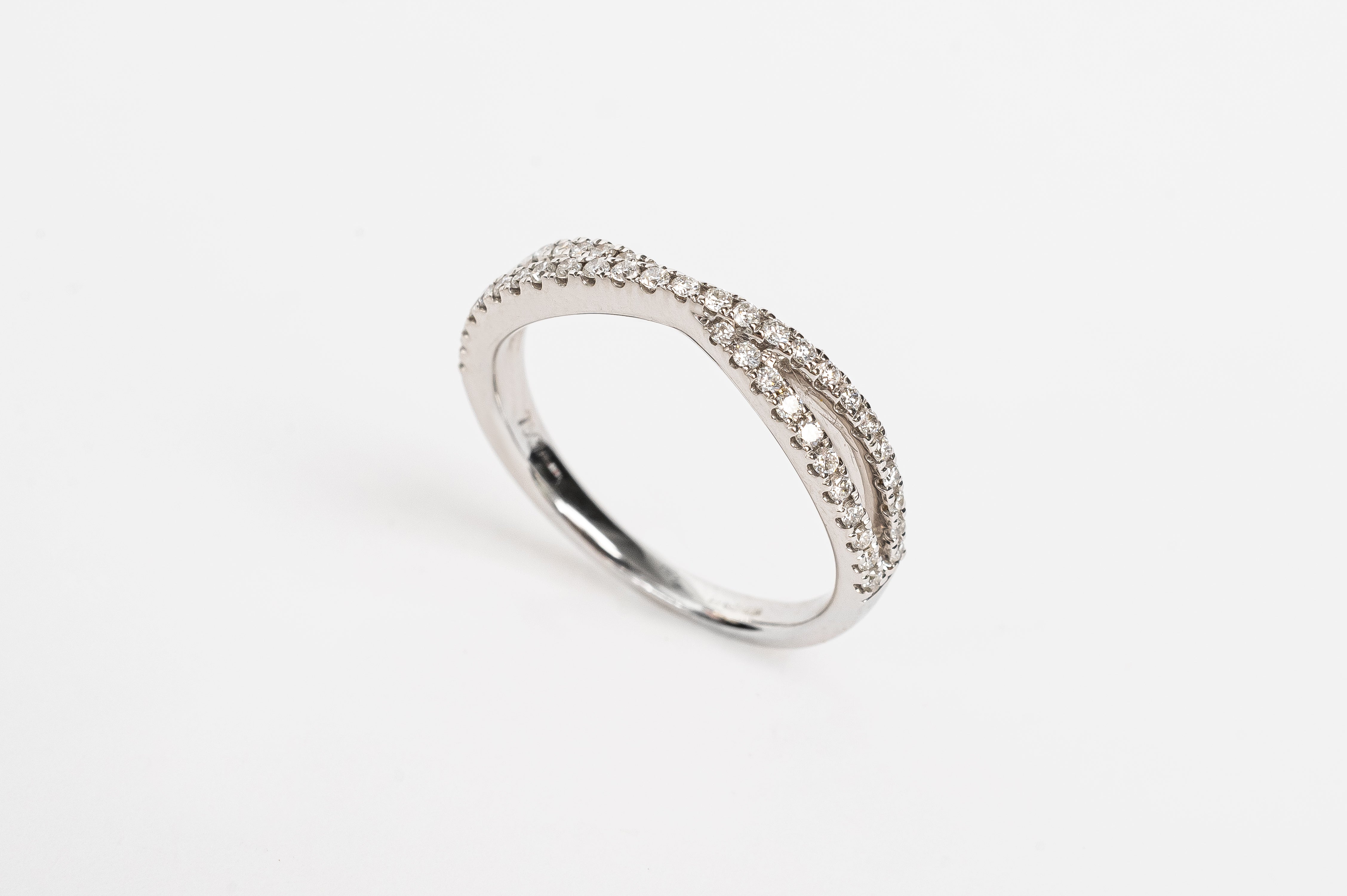 This cross over ring is made out of one band splitting into two diamond set bands and crossing in the middle. It is stunning! This ring can be worn alone or stacked together with others. What's your style?   18kt white gold