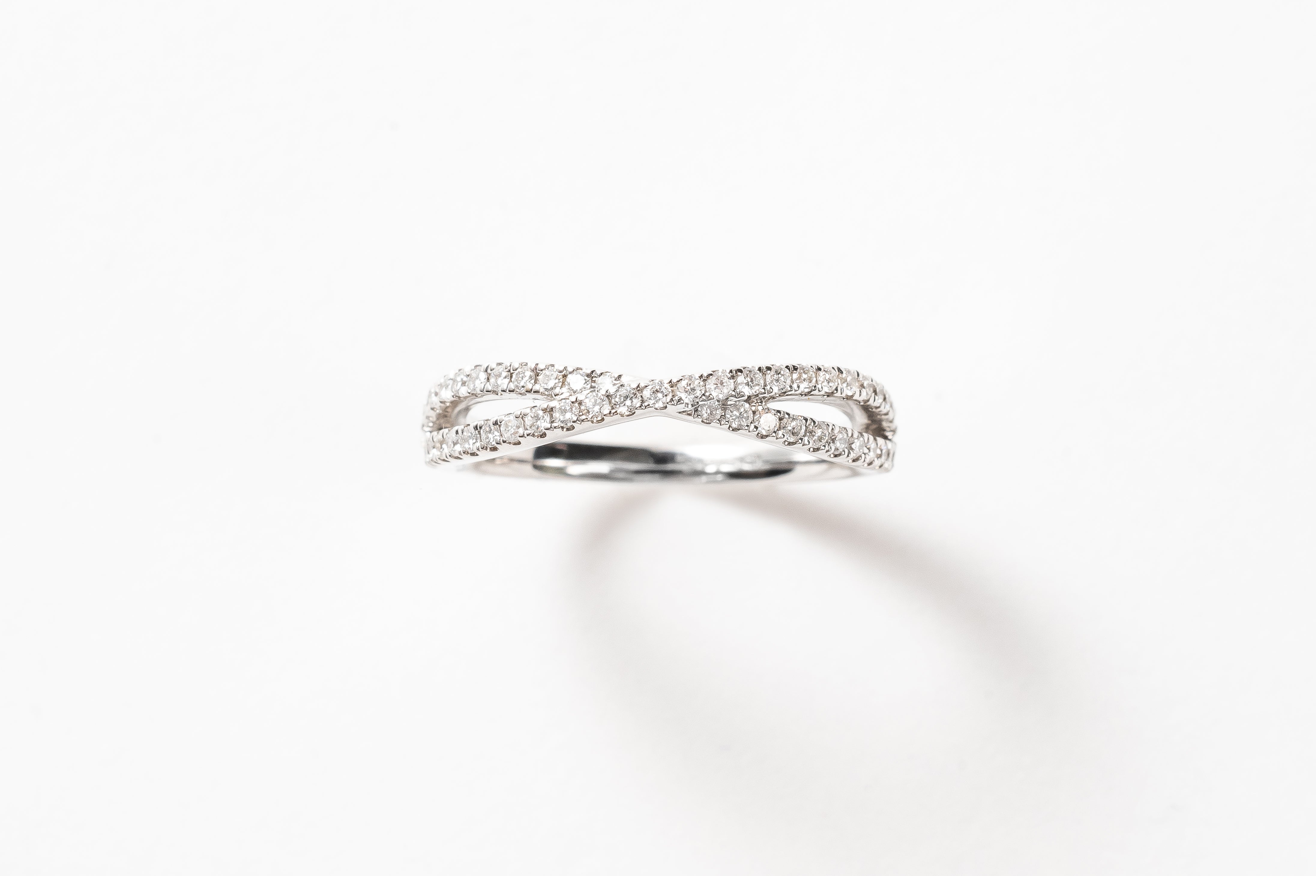 This cross over ring is made out of one band splitting into two diamond set bands and crossing in the middle. It is stunning! This ring can be worn alone or stacked together with others. What's your style?   18kt white gold