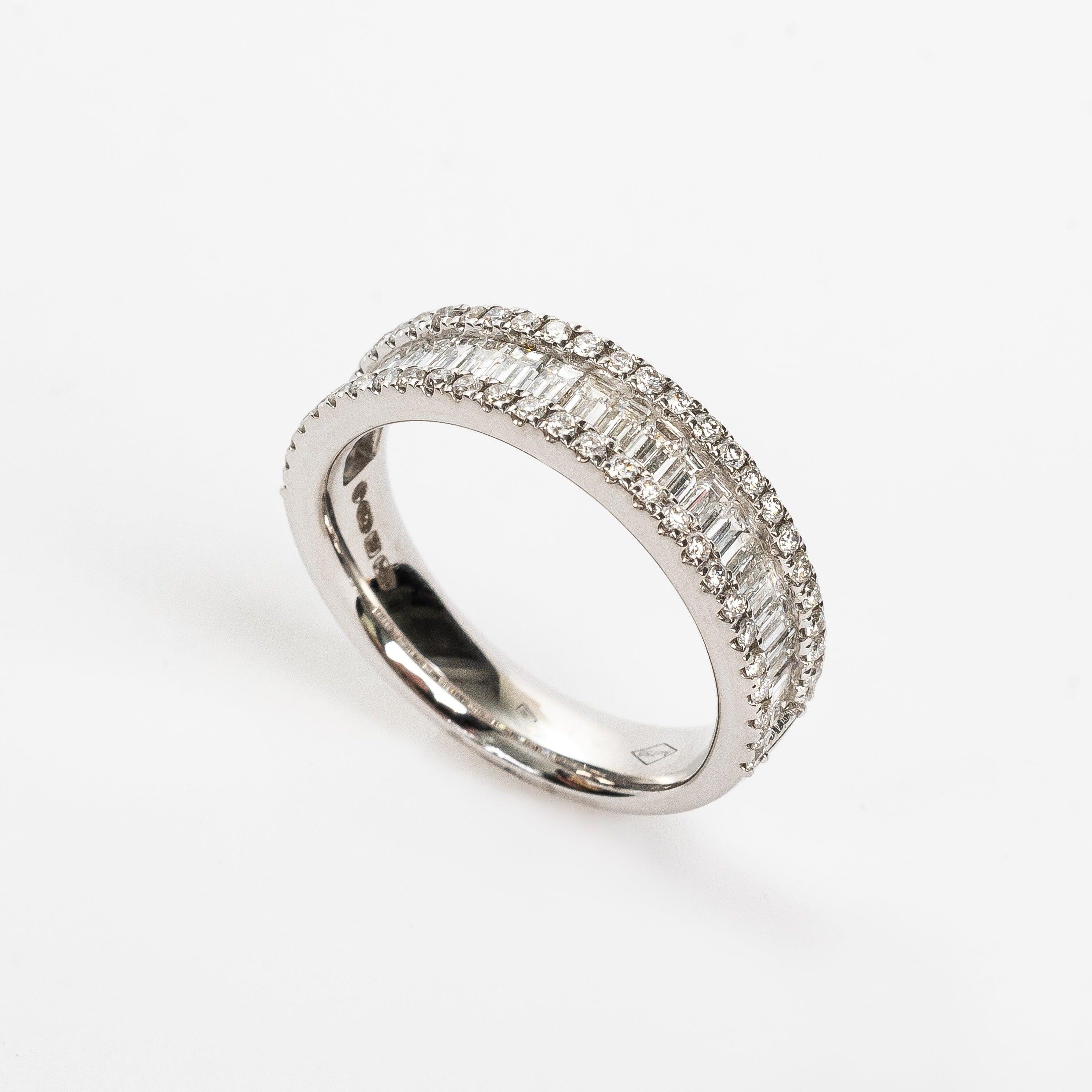 This baguette diamond ring is a showstopper! This new design is absolutely incredible. The baguette diamonds are set side by side to create sparkle from all angles. This triple row design has on both sides a row of round brilliant diamonds the close in the baguettes.   18kt white gold