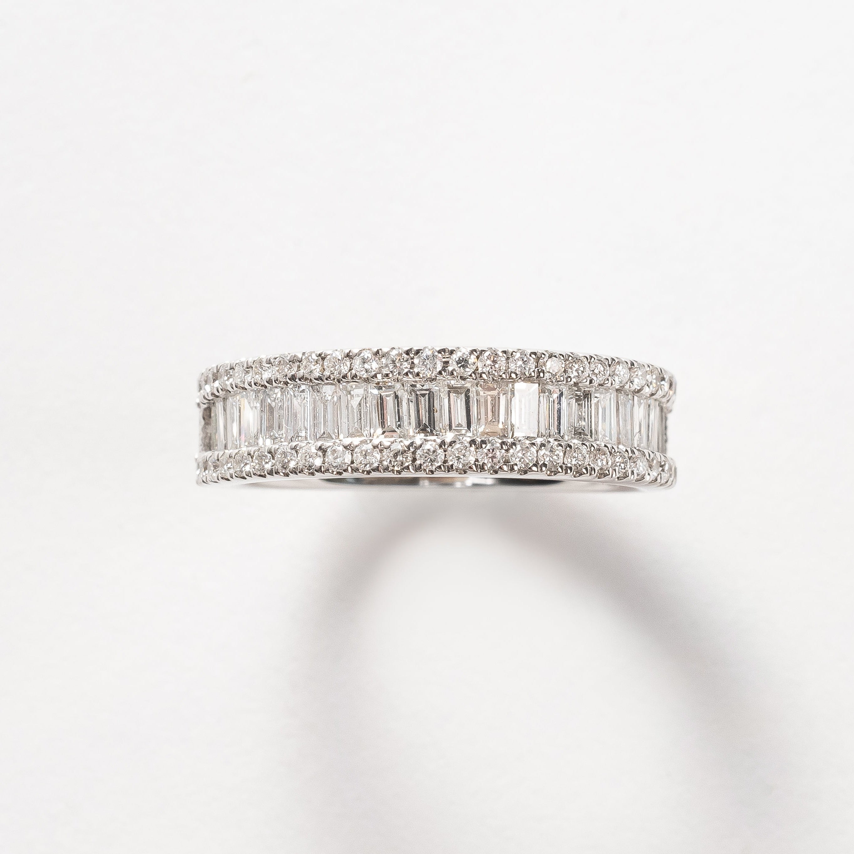 This baguette diamond ring is a showstopper! This new design is absolutely incredible. The baguette diamonds are set side by side to create sparkle from all angles. This triple row design has on both sides a row of round brilliant diamonds the close in the baguettes.   18kt white gold