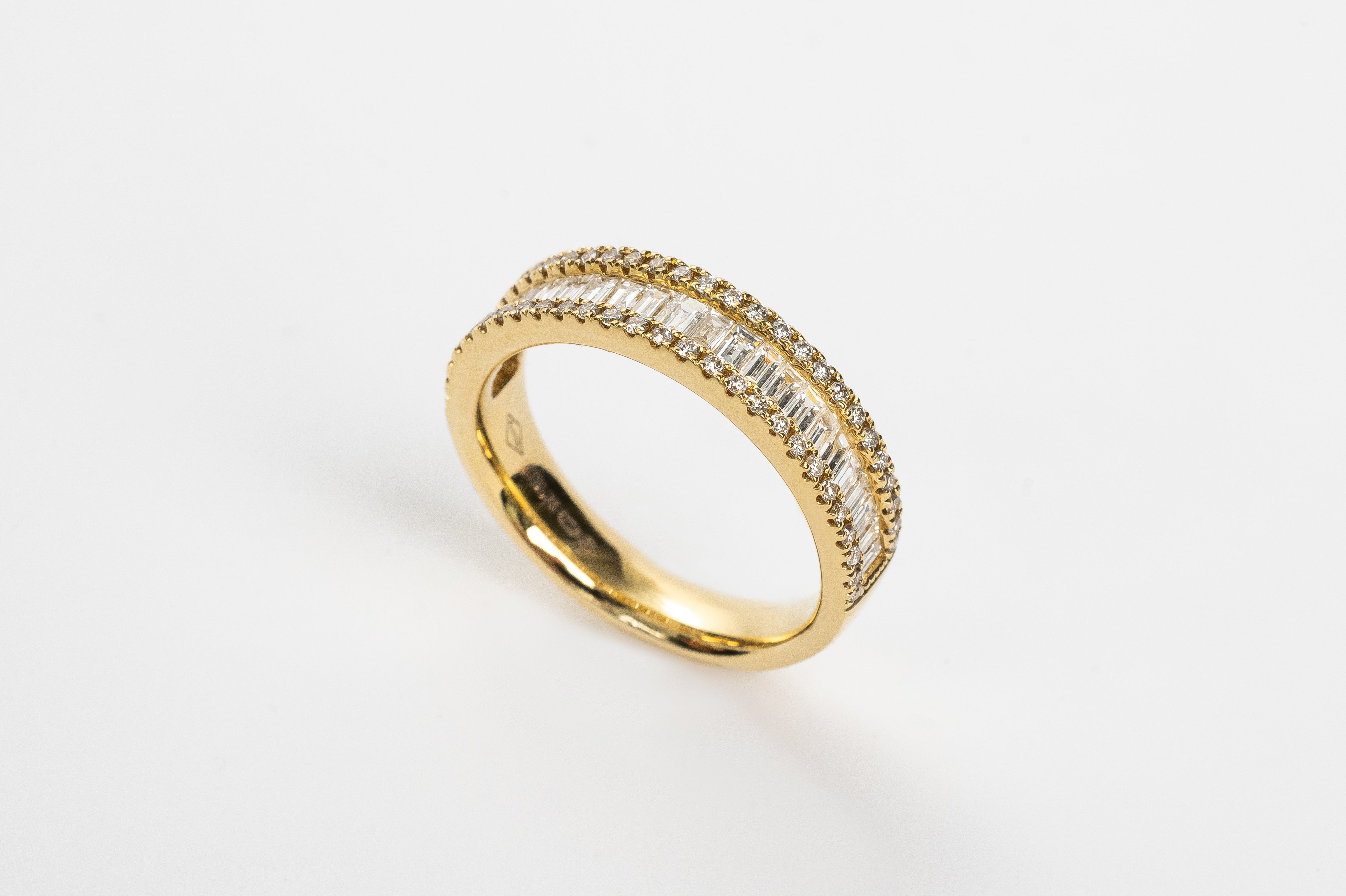 This baguette diamond ring is a showstopper! This new design is absolutely incredible. The baguette diamonds are set side by side to create sparkle from all angles. This triple row design has on both sides a row of round brilliant diamonds the close in the baguettes.   18kt yellow gold