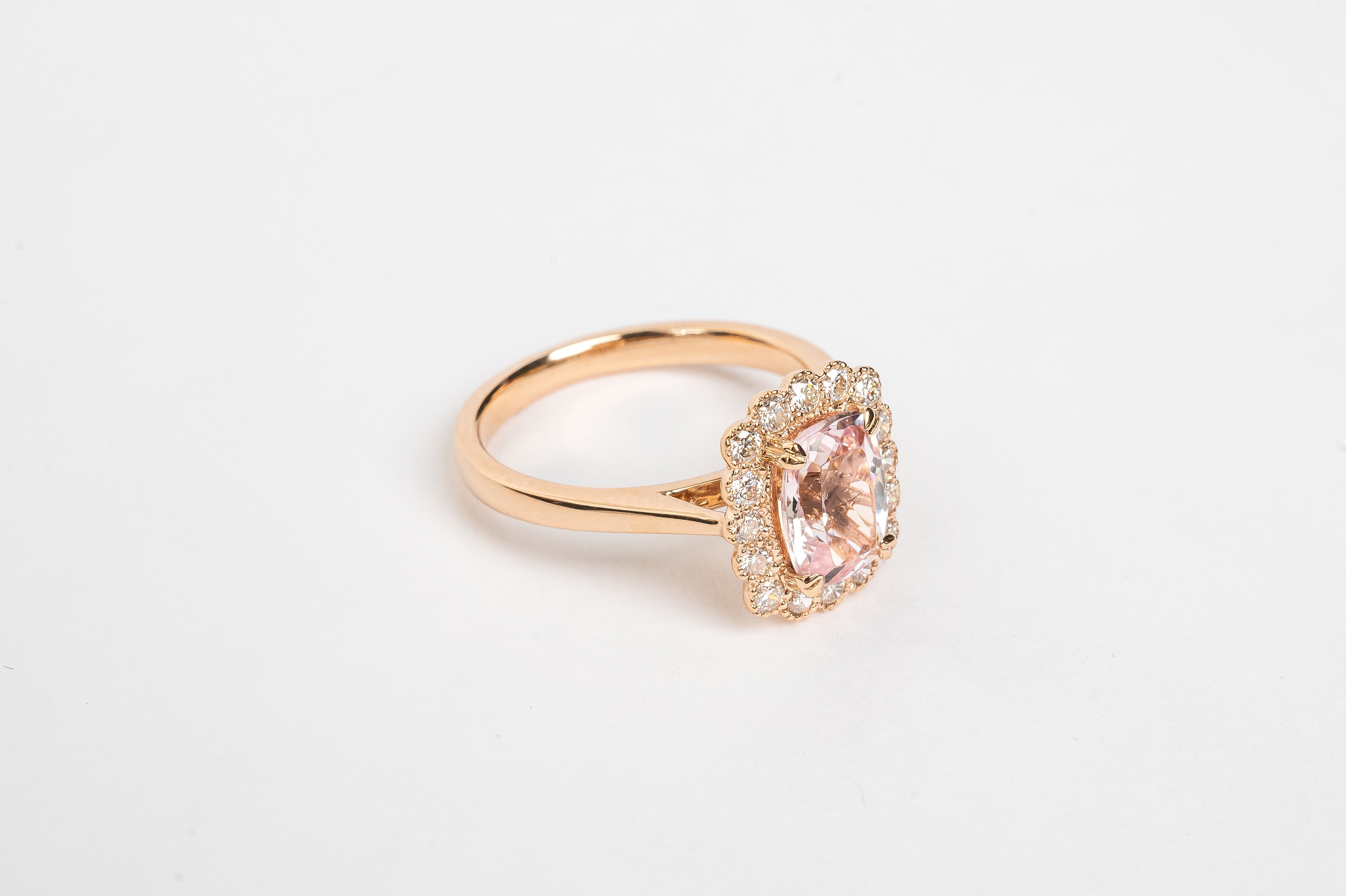 What a beautiful ring! The Morganite is cut in a cushion shape and surrounded by diamond halo of round brilliant diamonds. The soft peachy pink color of the stone matches so beautifully with the rose metal color of the ring.   18kt rose gold