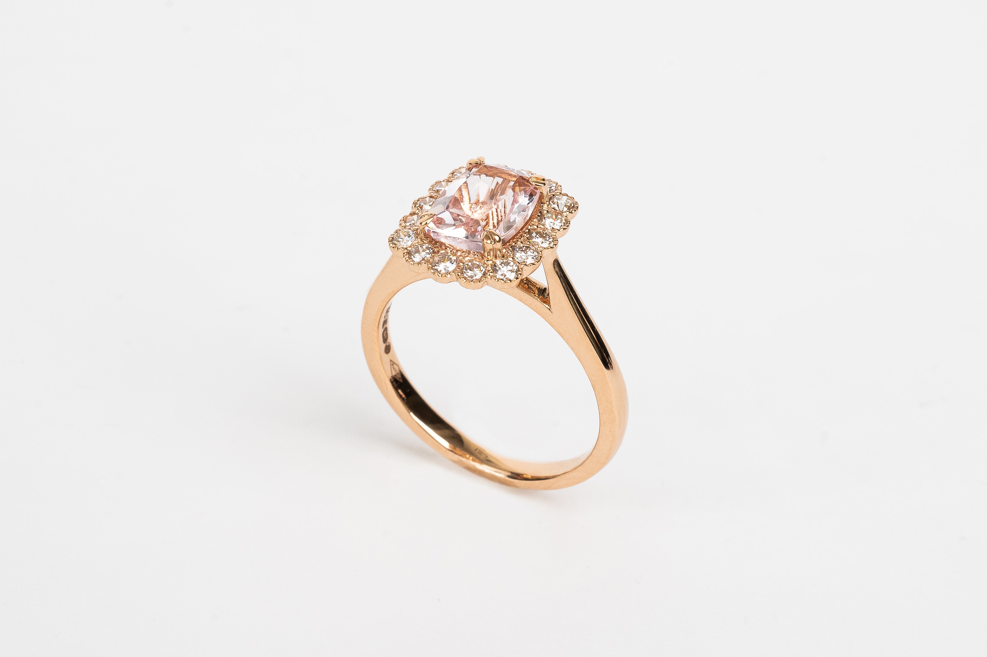 What a beautiful ring! The Morganite is cut in a cushion shape and surrounded by diamond halo of round brilliant diamonds. The soft peachy pink color of the stone matches so beautifully with the rose metal color of the ring.   18kt rose gold