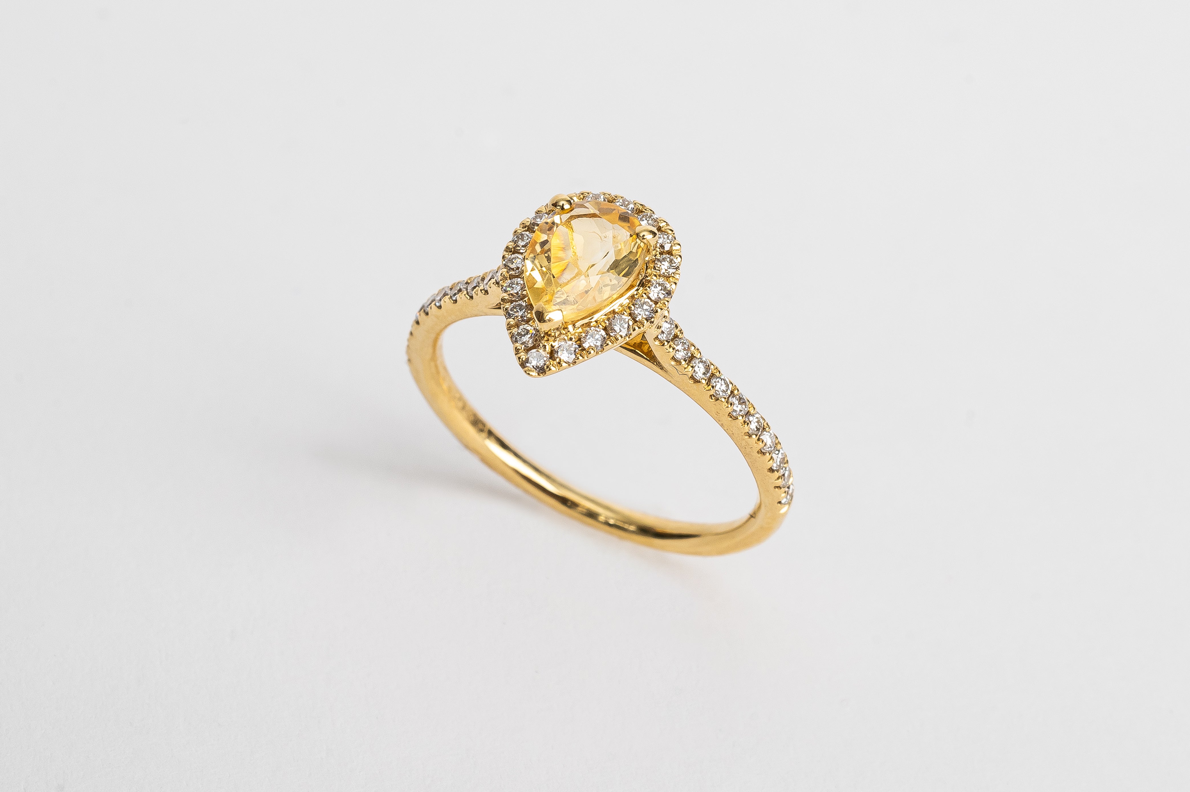 This yellow golden ring is set with round diamonds on the side, and a pear cut Citrine gemstone in the center, surrounded by a pear shaped halo.  This ring is so beautiful on its own and needs no stacked rings on the side.   This gemstone is believed to have healing powers. It has a warm yellow hue. Citrine is one of the most popular gemstones in the quartz family. 