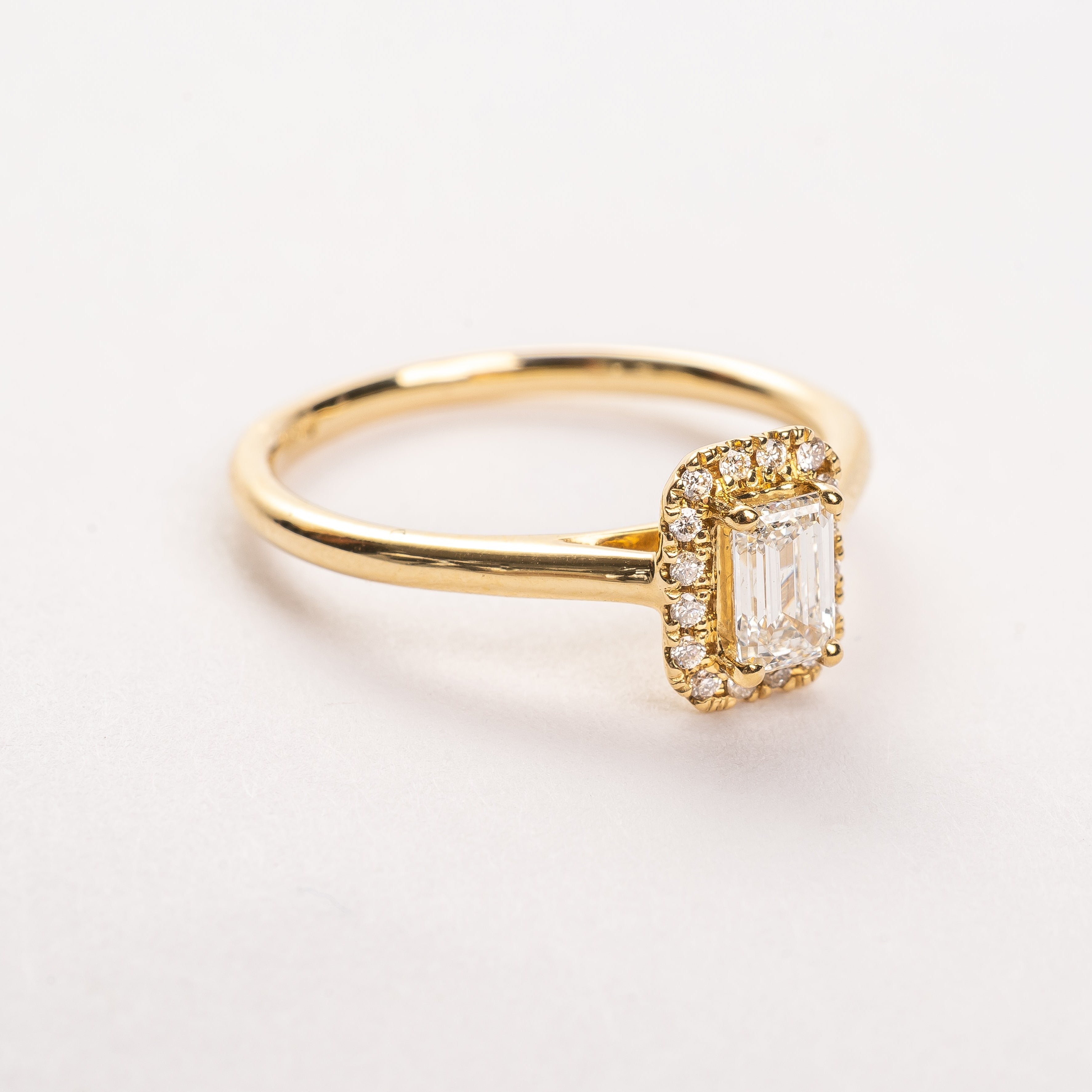 This gorgeous emerald cut Diamond ring made of yellow gold is beautiful. The band is plain and simple, this makes the diamond with the diamond halo stunning on your hand. This ring is made too fit a wedding band. 