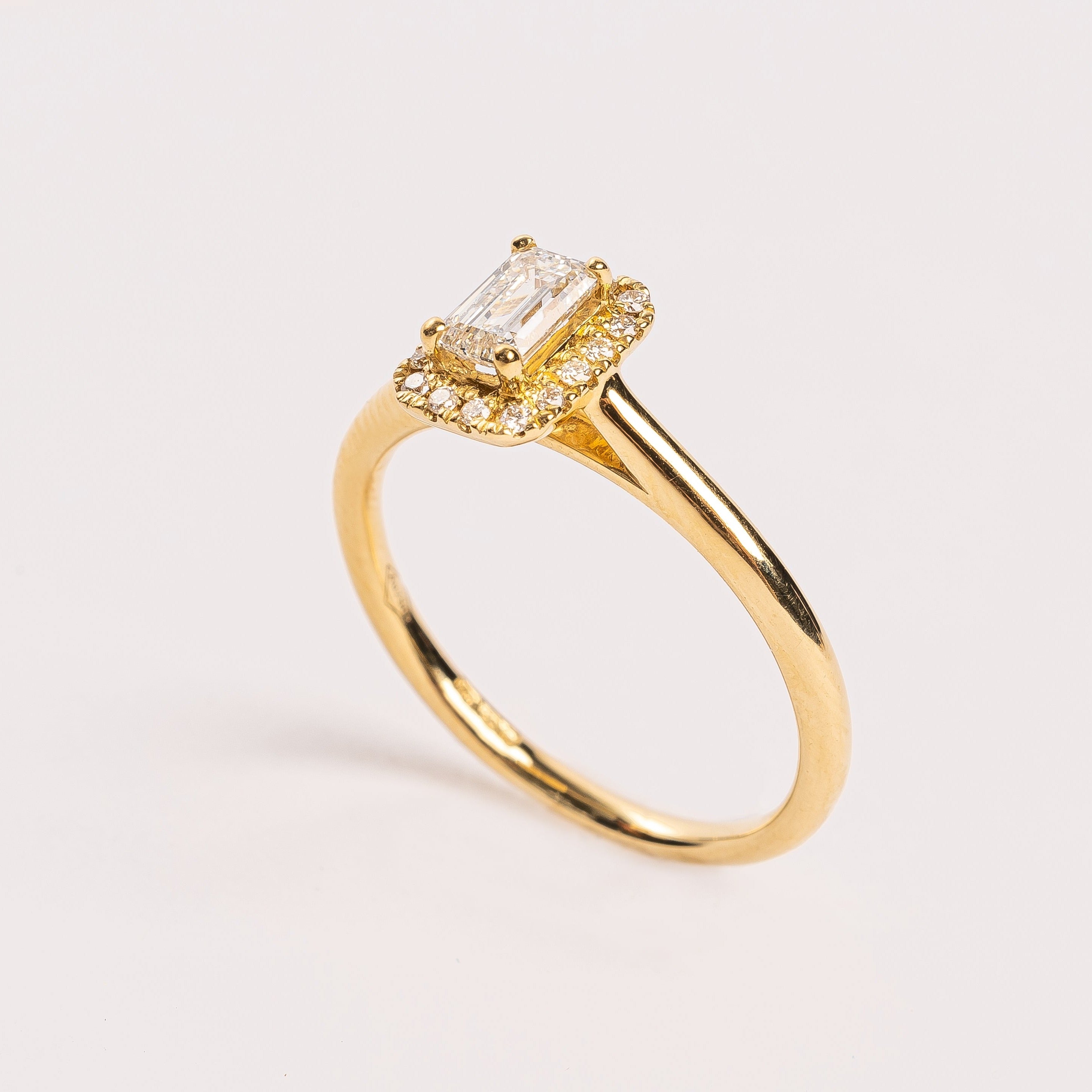 This gorgeous emerald cut Diamond ring made of yellow gold is beautiful. The band is plain and simple, this makes the diamond with the diamond halo stunning on your hand. This ring is made too fit a wedding band. 