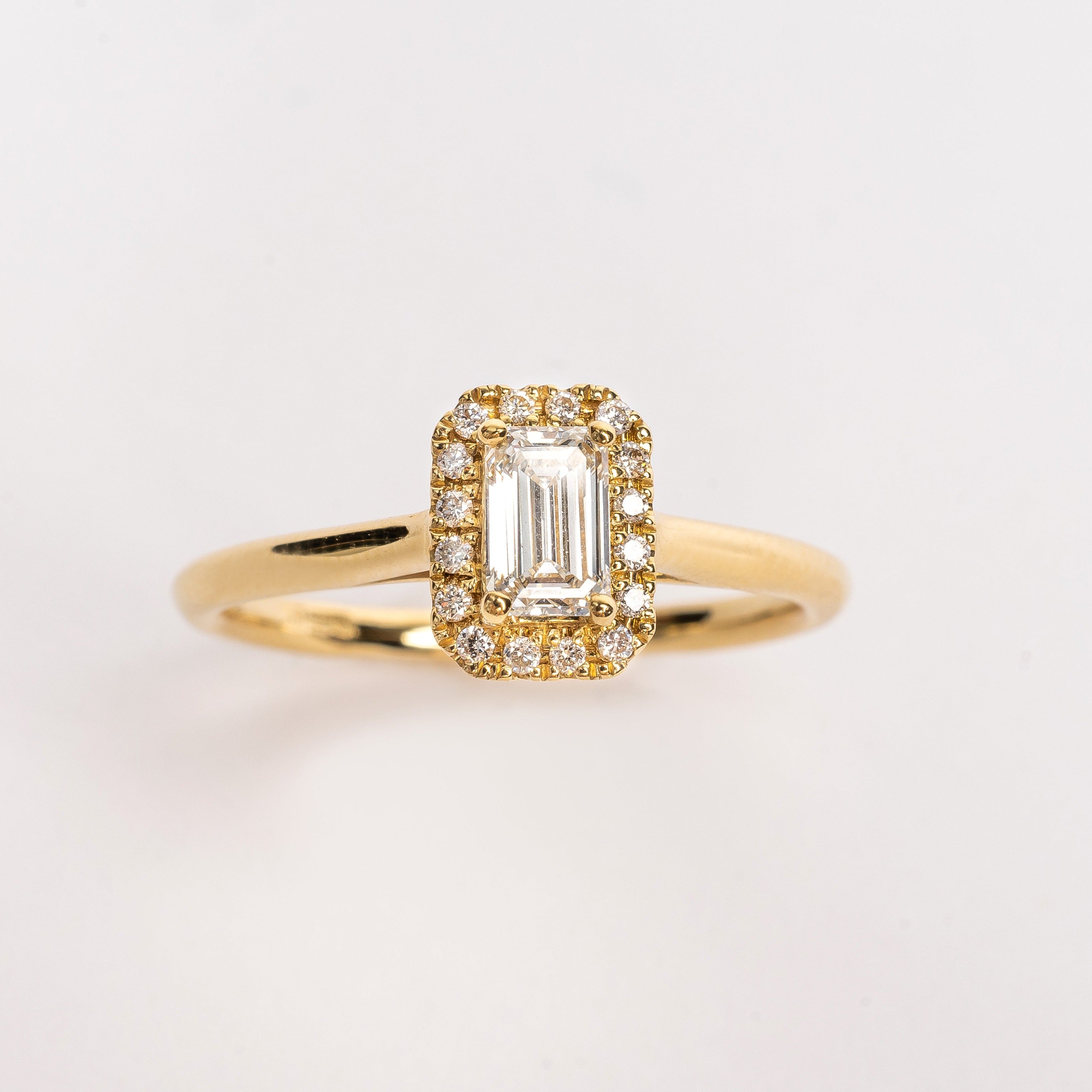 This gorgeous emerald cut Diamond ring made of yellow gold is beautiful. The band is plain and simple, this makes the diamond with the diamond halo stunning on your hand. This ring is made too fit a wedding band. 