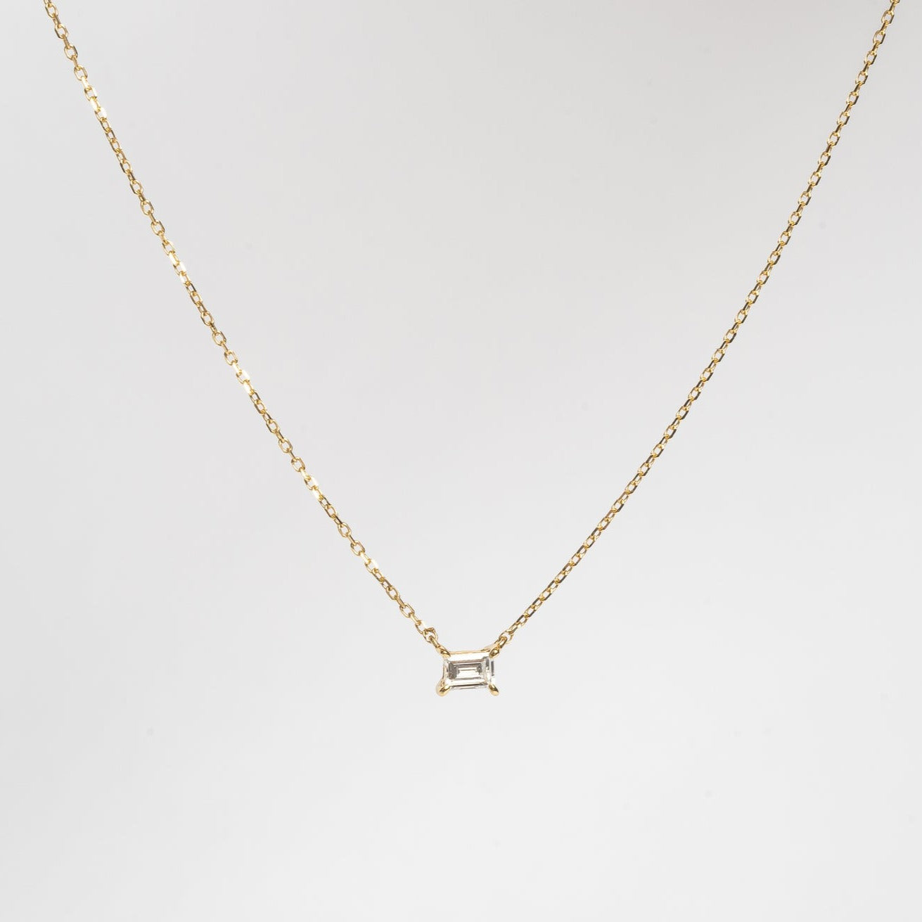 This mini baguette necklace is so refined and elegant. This necklace gives your neck a subtle touch of sparkle. This necklace is elegant by itself, but also very nice to layer with other necklaces.   18kt yellow gold 4.4 mm x 3.3 mm Baguette stone set with four claws Total diamond weight for the baguette is approx. 0.20ct Necklace length 40cm