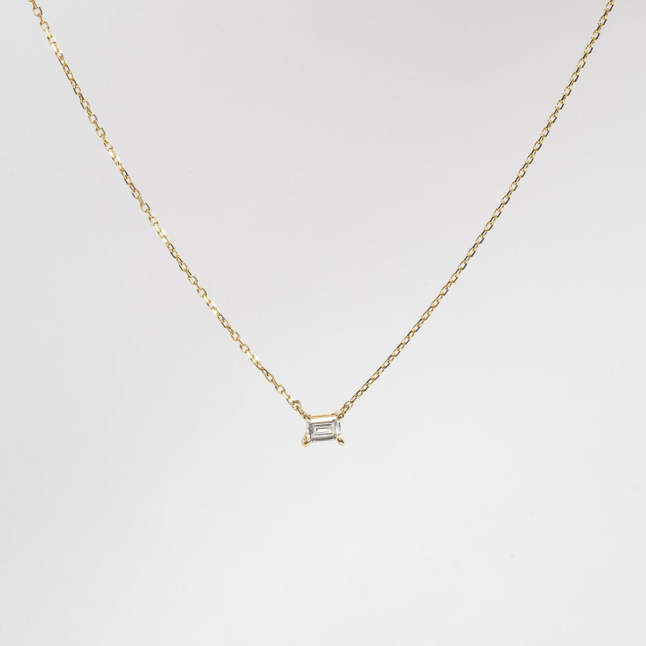 This mini baguette necklace is so refined and elegant. This necklace gives your neck a subtle touch of sparkle. This necklace is elegant by itself, but also very nice to layer with other necklaces.   18kt yellow gold 4.4 mm x 3.3 mm Baguette stone set with four claws Total diamond weight for the baguette is approx. 0.20ct Necklace length 40cm