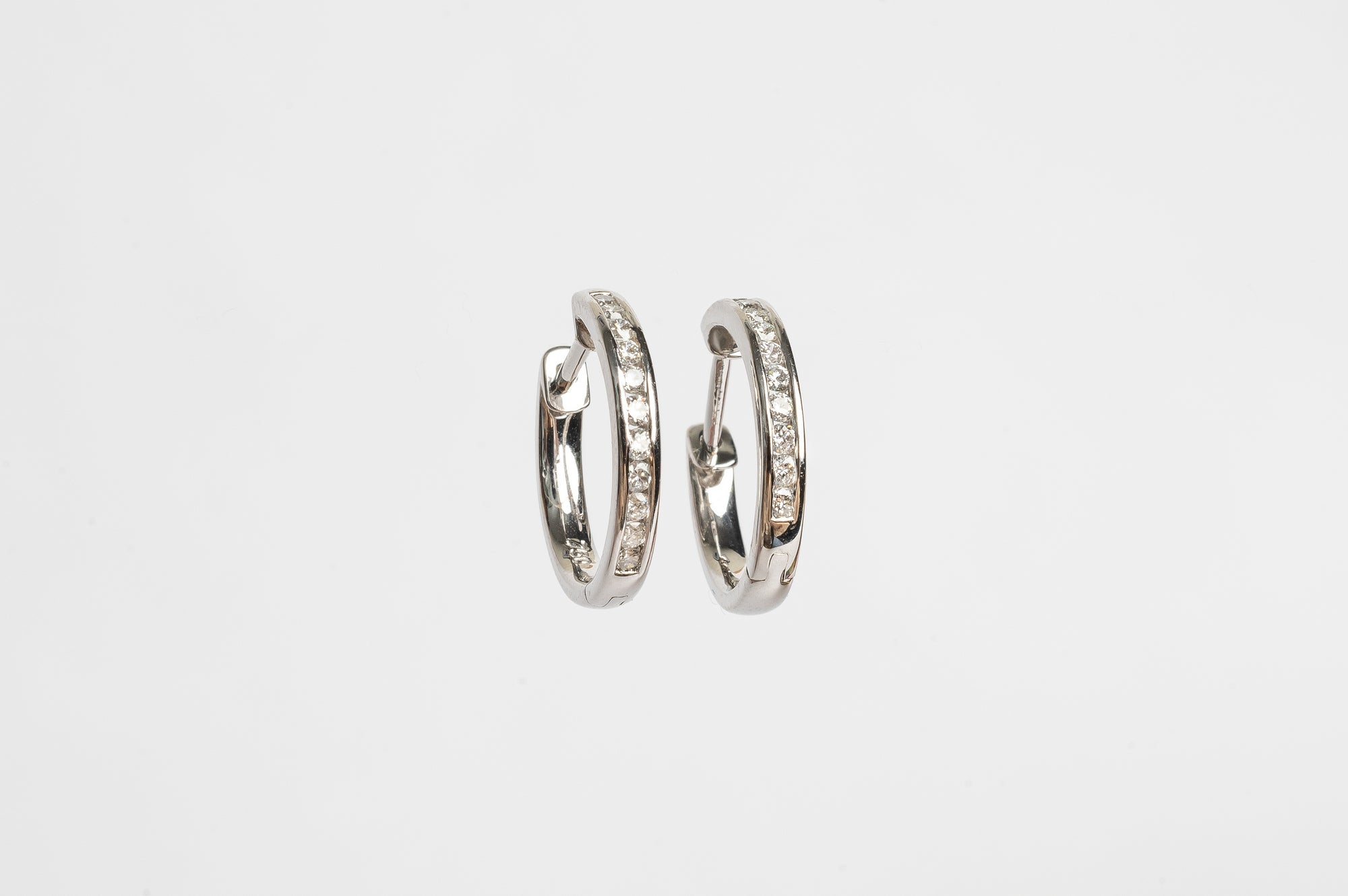 These channel set diamond hoops are on trend. The look gives a river of diamonds on each ear. Diamonds are set in 'rail tracks' which gives a more sophisticated look. The diamonds are set in the most safe way. 