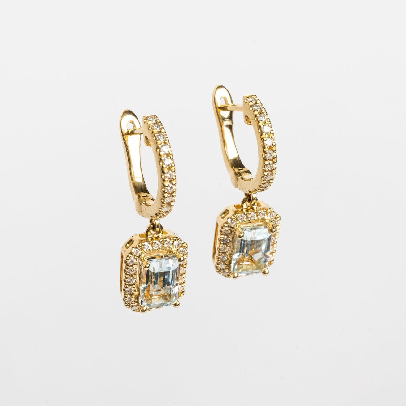 These beautiful pendant earrings with a blue Emerald cut Aquamarine center stone are elegant and finish every look.  The blue makes you happy and compliment your eyes.   18kt yellow gold  6mm x 4mm Emerald cut blue Aquamarine each earring 