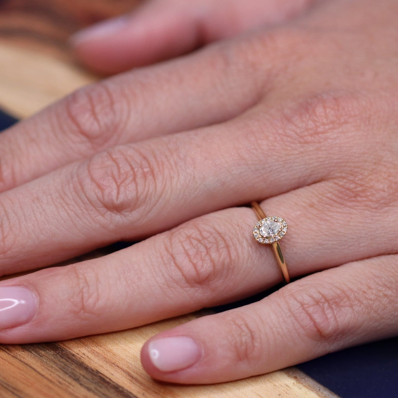 This is your engagement ring. This yellow golden ring is set with a brilliant diamond surrounded by a diamond halo. It looks perfect in its simplicity yet the halo makes the stone look more big.