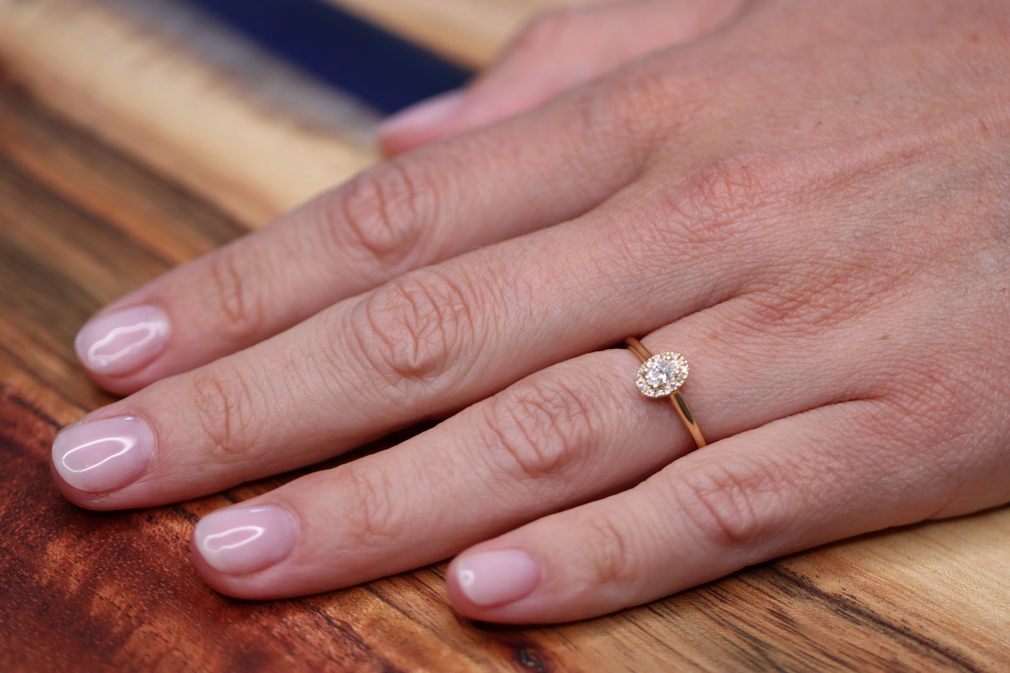 This is your engagement ring. This yellow golden ring is set with a brilliant diamond surrounded by a diamond halo. It looks perfect in its simplicity yet the halo makes the stone look more big.