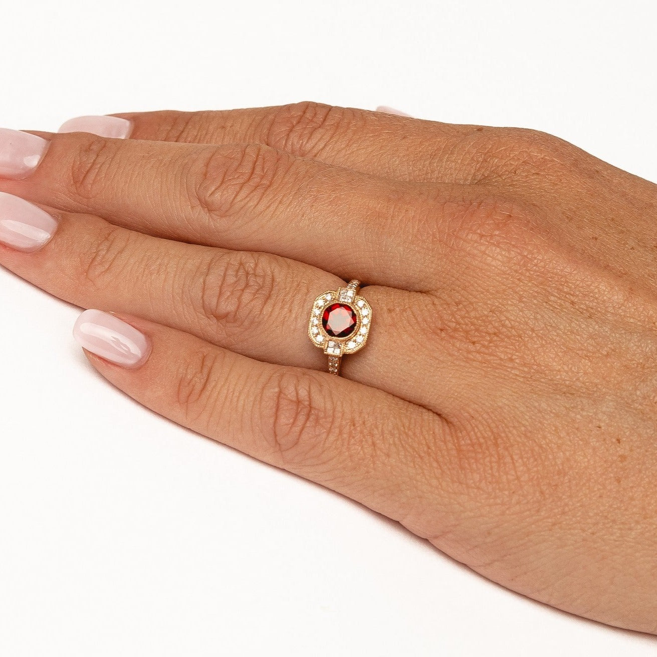 A vintage designed ring with a beautiful deep red garnet gemstone surrounded by natural diamonds.   18kt rose gold  Total diamond weight for the ring approx. 0.33ct round brilliant diamonds Red garnet: 6mm