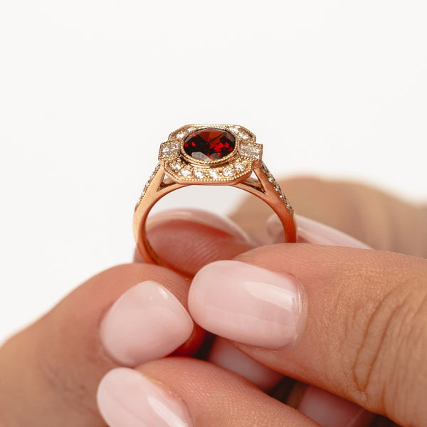 A vintage designed ring with a beautiful deep red garnet gemstone surrounded by natural diamonds.   18kt rose gold  Total diamond weight for the ring approx. 0.33ct round brilliant diamonds Red garnet: 6mm